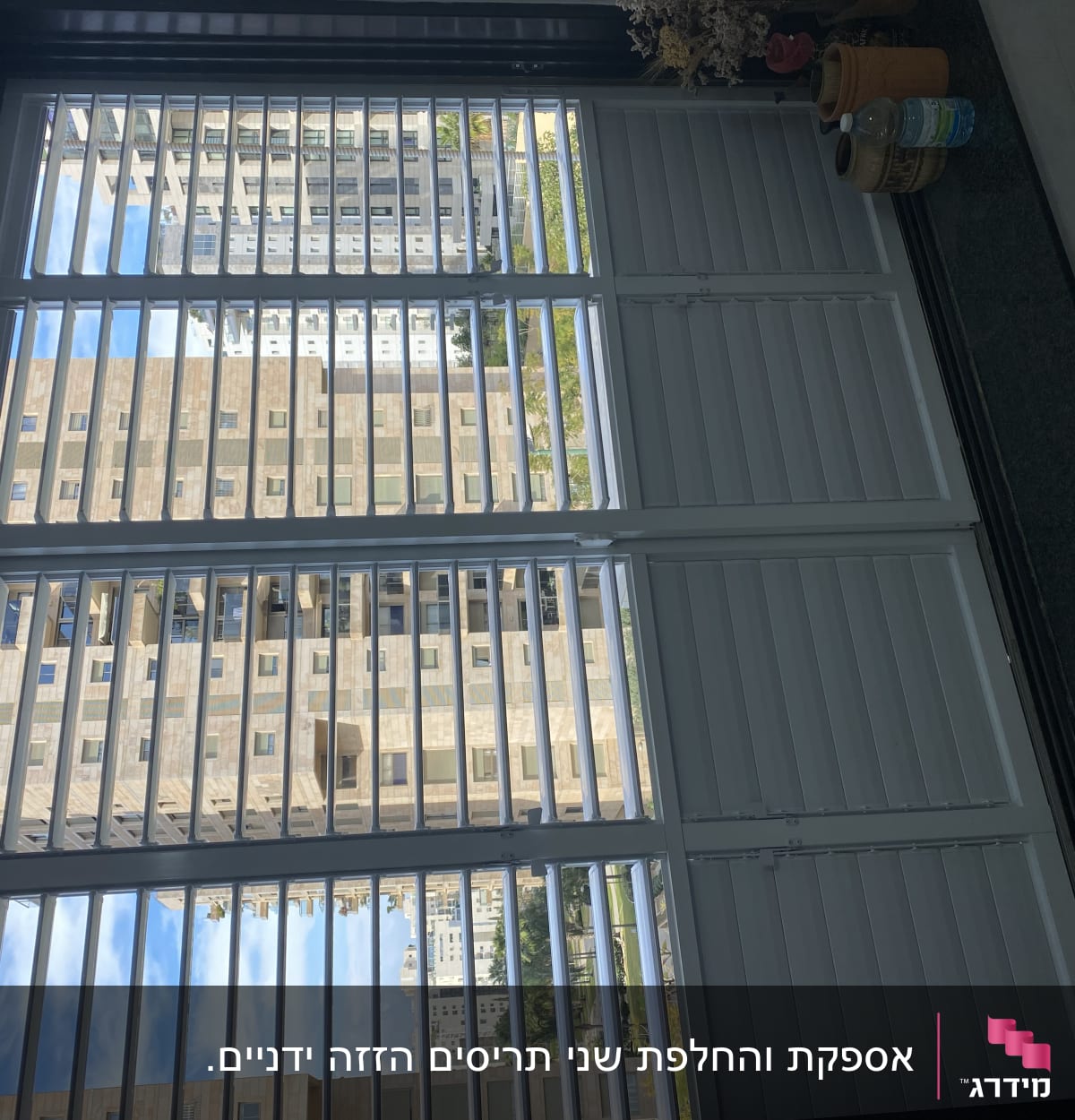 תריסים לבנים פתוחים עם נוף עירוני ברקע